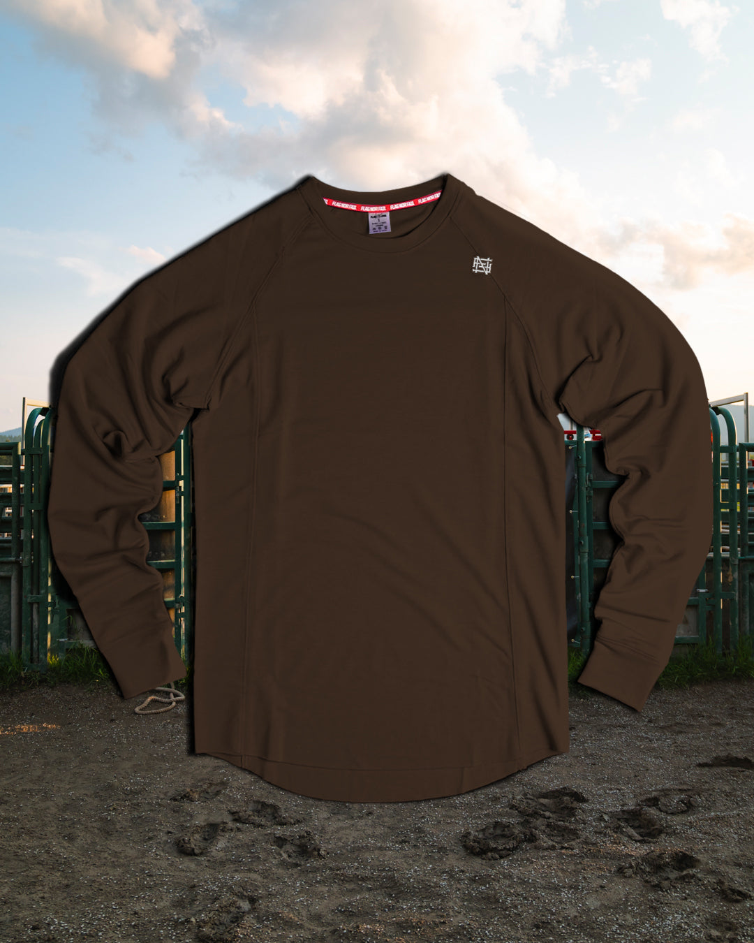 Brown long-sleeve shirt with logos on a textured surface with a blurred background