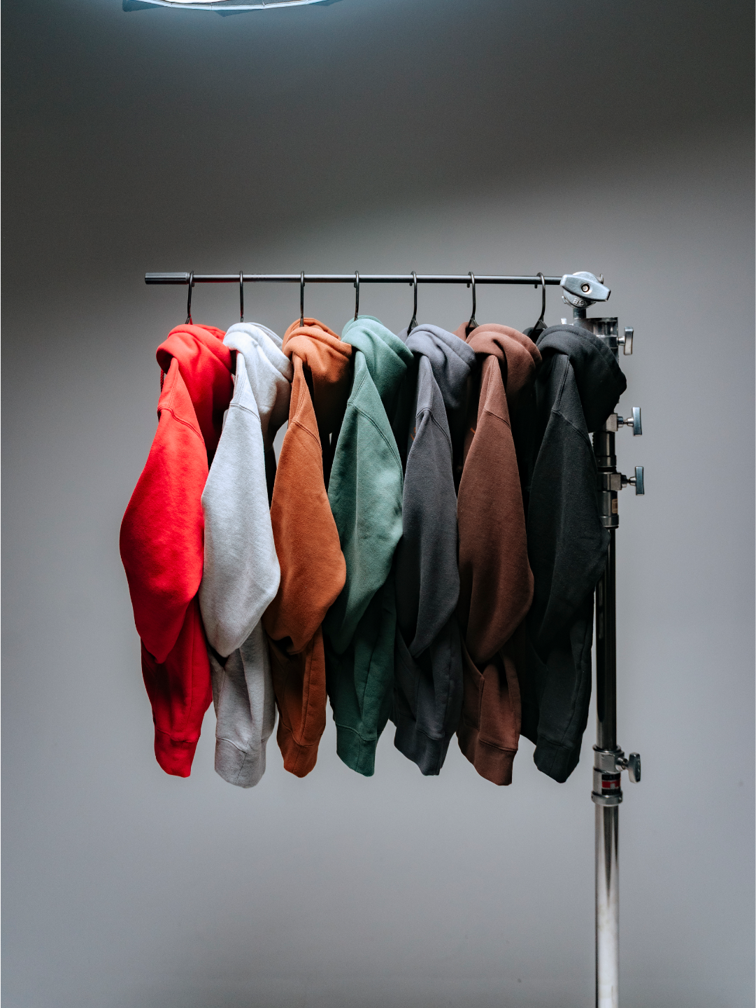 a side view of a row of anthem hoodies on hangars within a studio