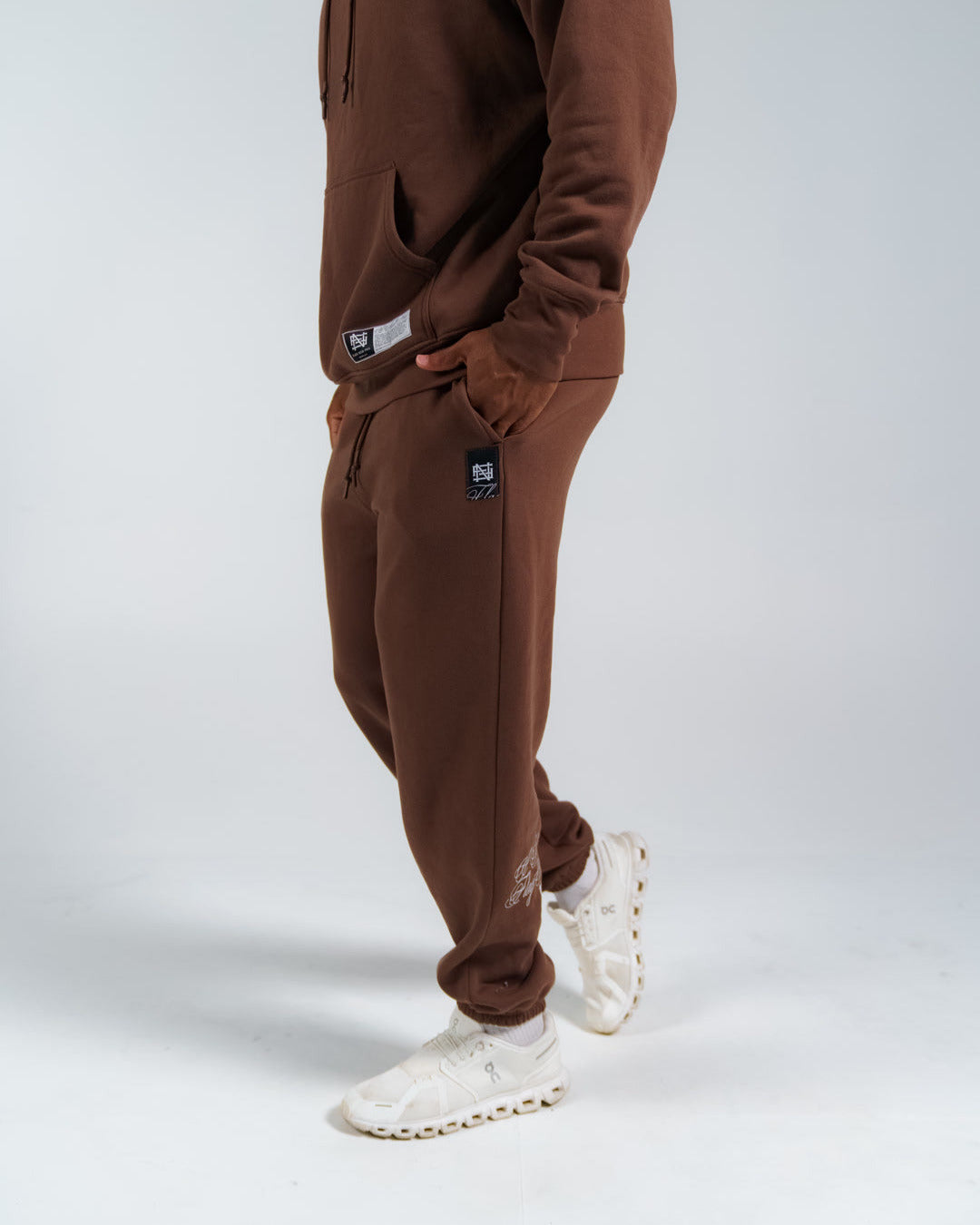 Person wearing a brown fleece set with white sneakers on a light gray background