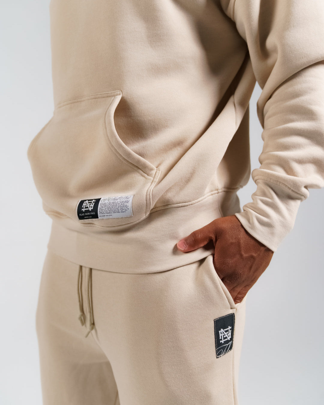 Cream colored tracksuit with brand logo on a light gray background
