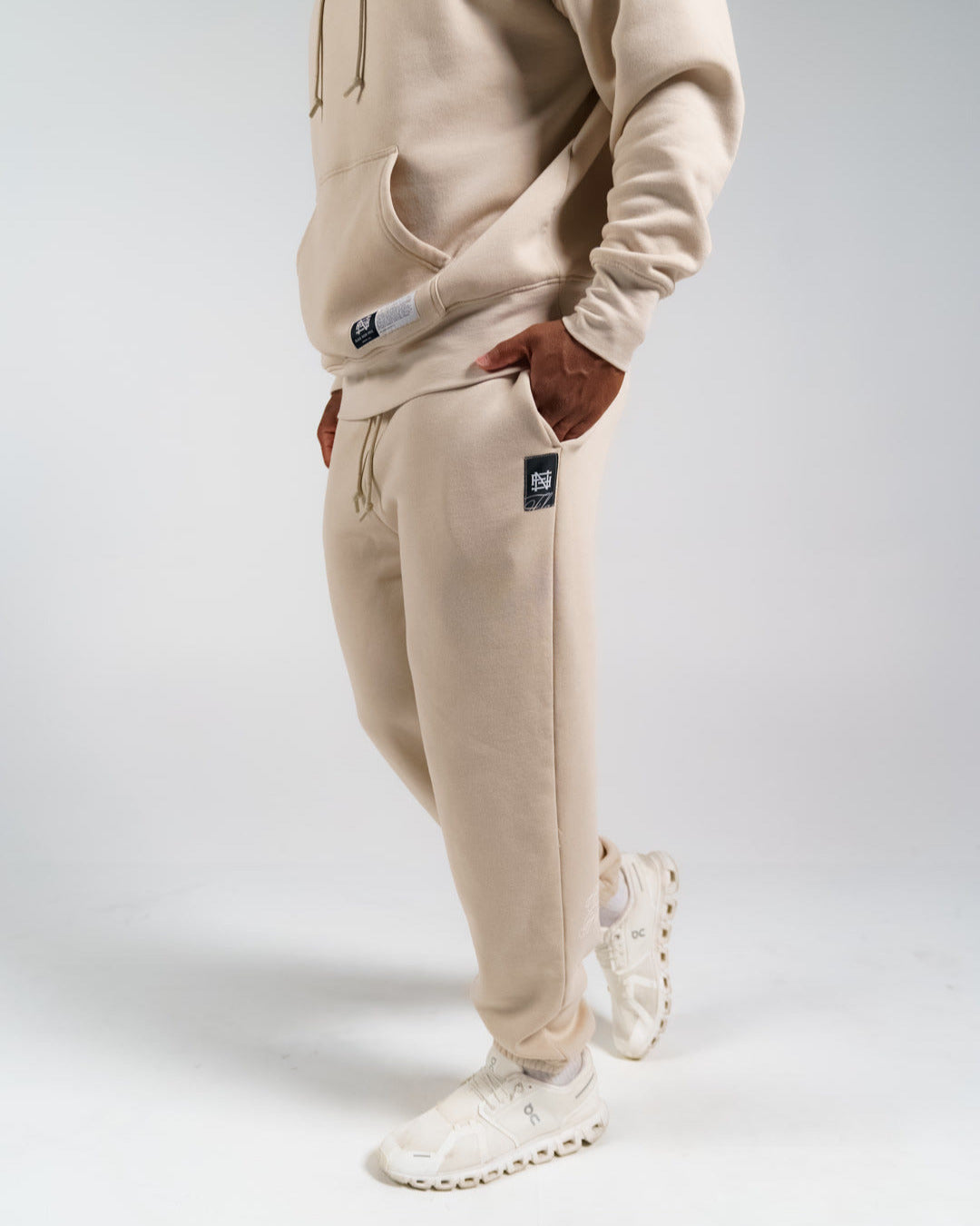 Person wearing a cream fleece set with white sneakers on a light gray background