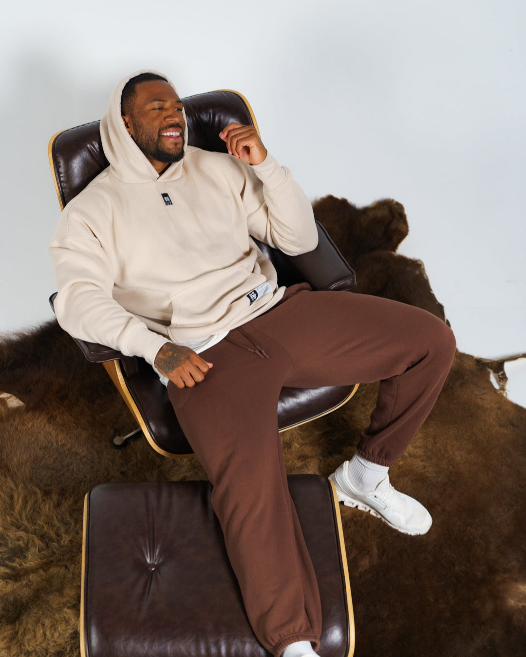 Man sitting on a leather chair on a buffalo hide with a neutral background
