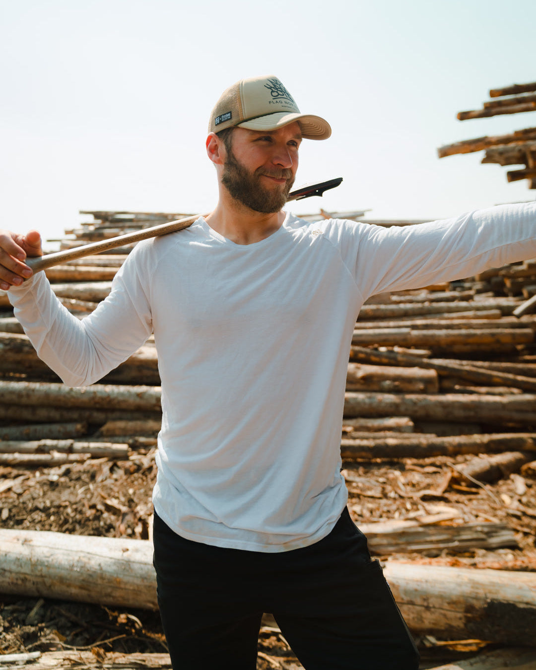 Man holding a axe with stacked logs in the background