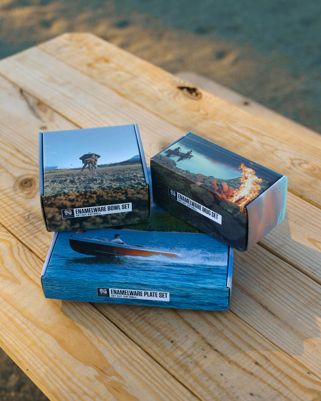 Three boxed sets on a wooden picnic table with a blurred natural background