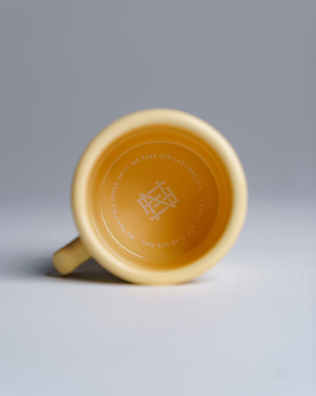 Yellow enamel mug with a logo on a gray background