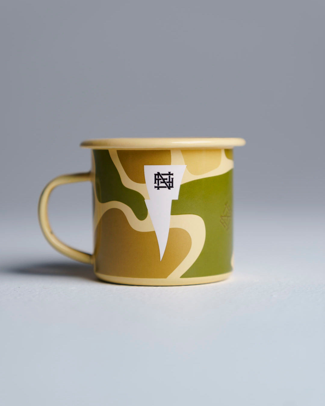 Enamel mug with FNF Monogram against studio background