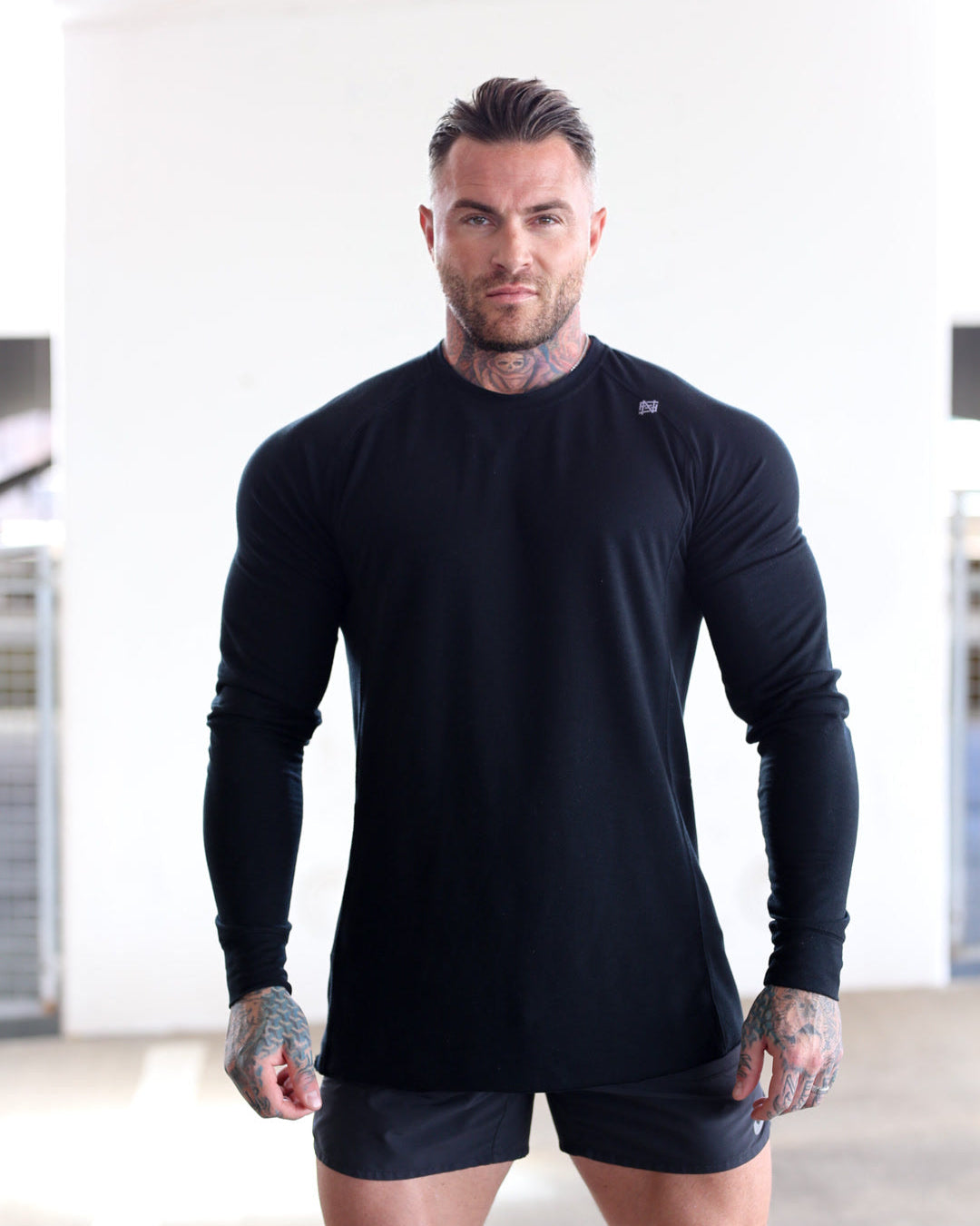 Man wearing a black long-sleeve athletic shirt and shorts in a gym setting
