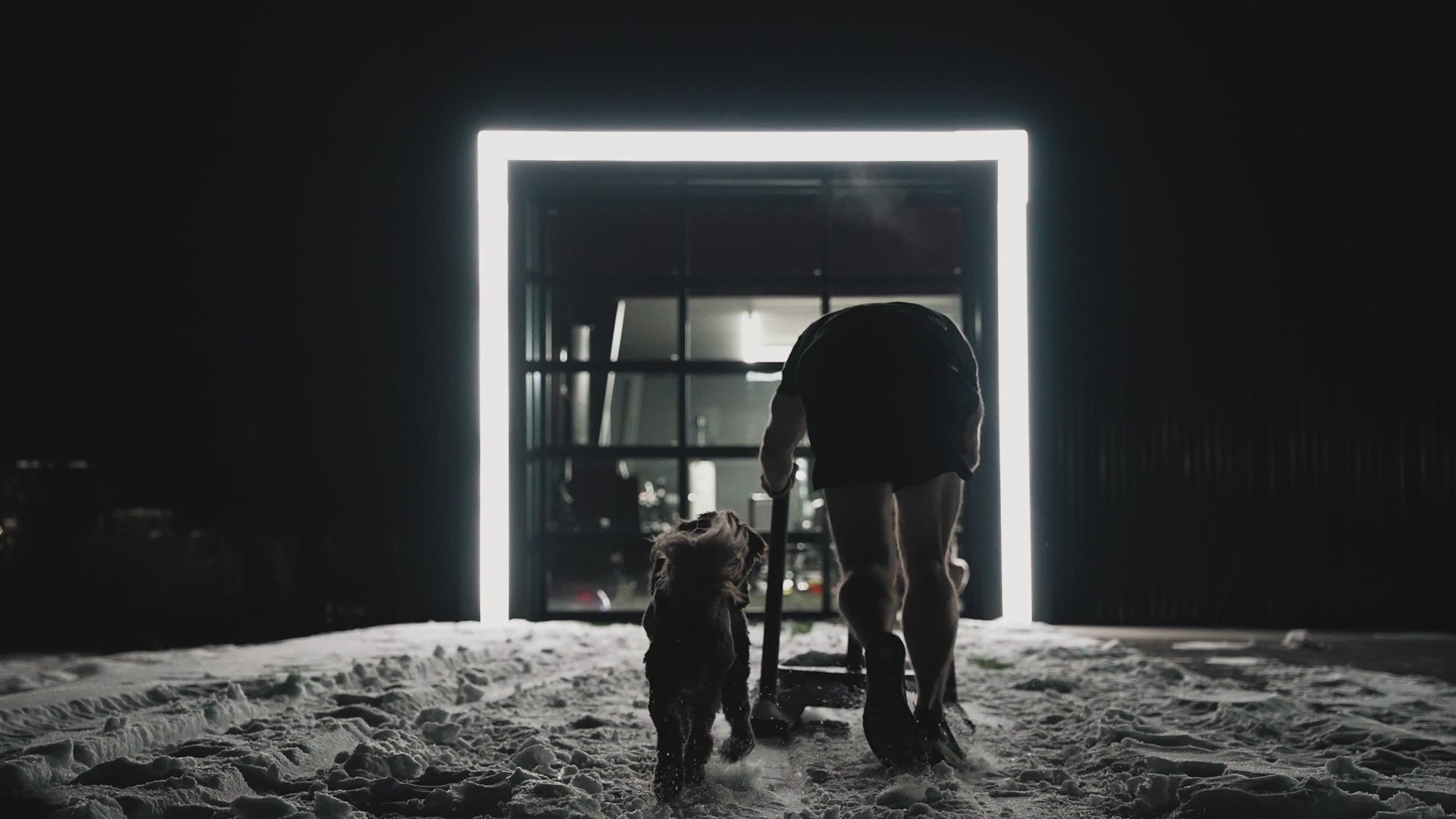 Cinematic video of Austin pushing a sled outside through the snow at night in front of the flag nor fail hq building.